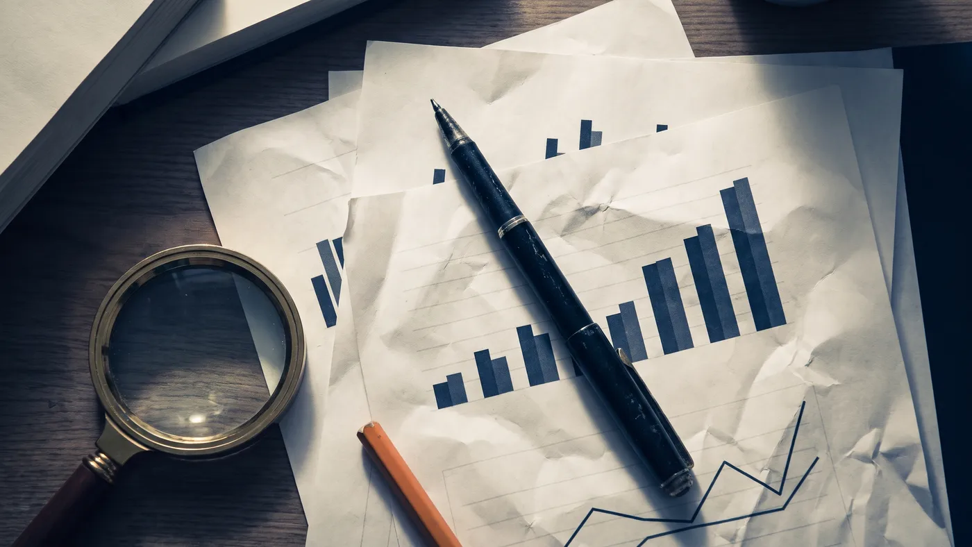 Printed charts on a desk under a magnifying glass